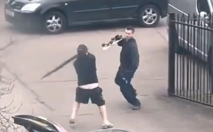 Hombres se pelean con un monopatín y un paraguas