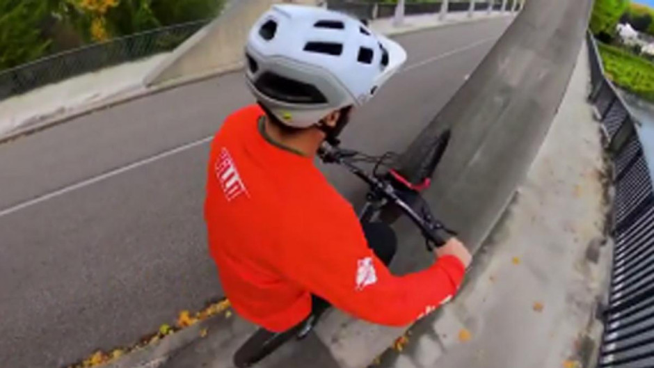 Ciclista cruza río sobre la estructura superior de un puente